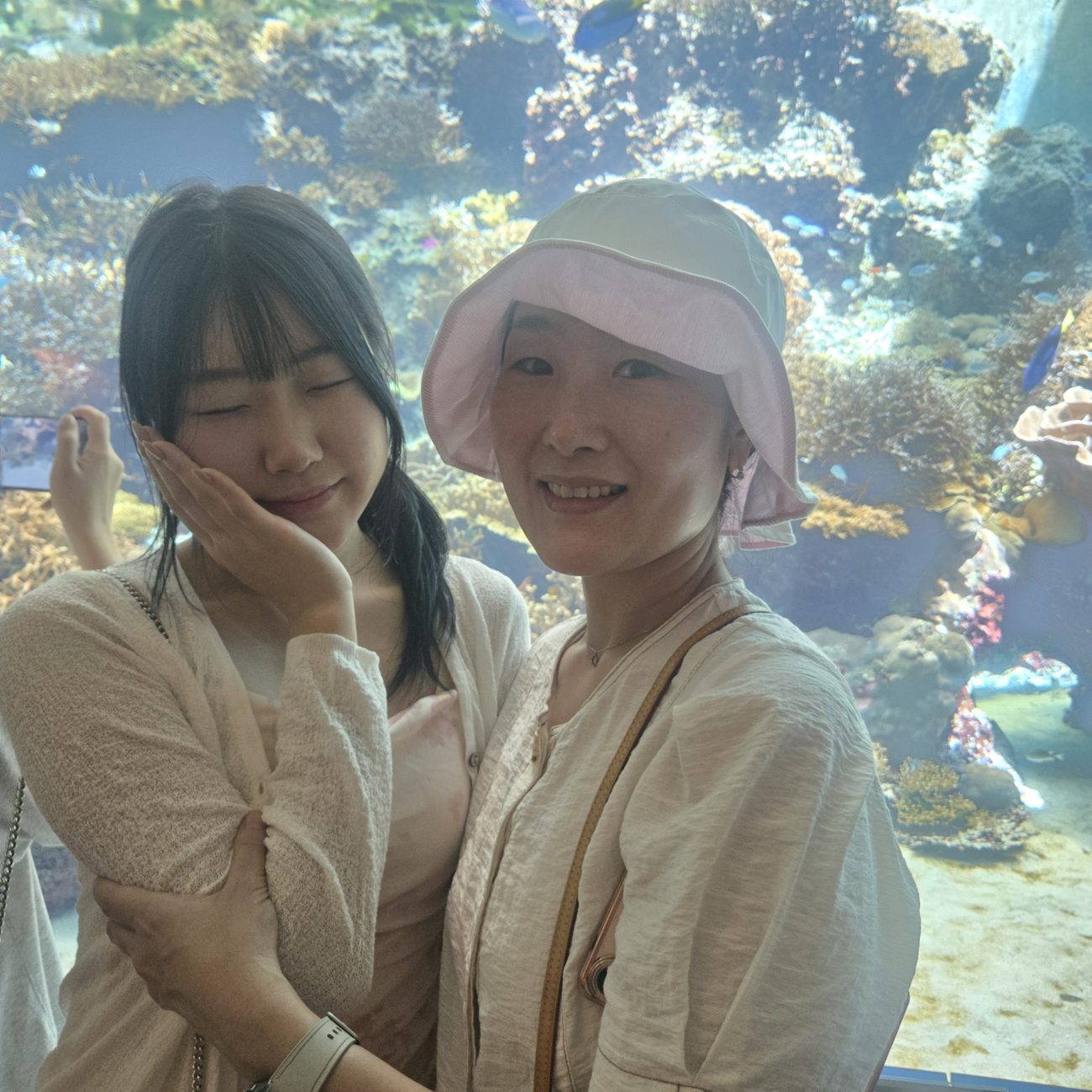 산호초 수조 앞에서 다정하게 선 엄마와 딸