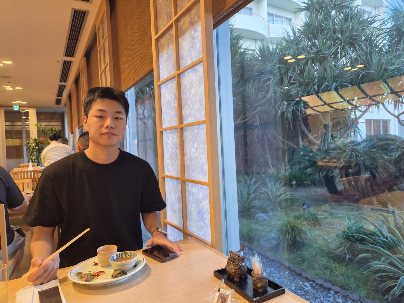 정원이 보이는 창가 자리에서 아침을 먹는 아들