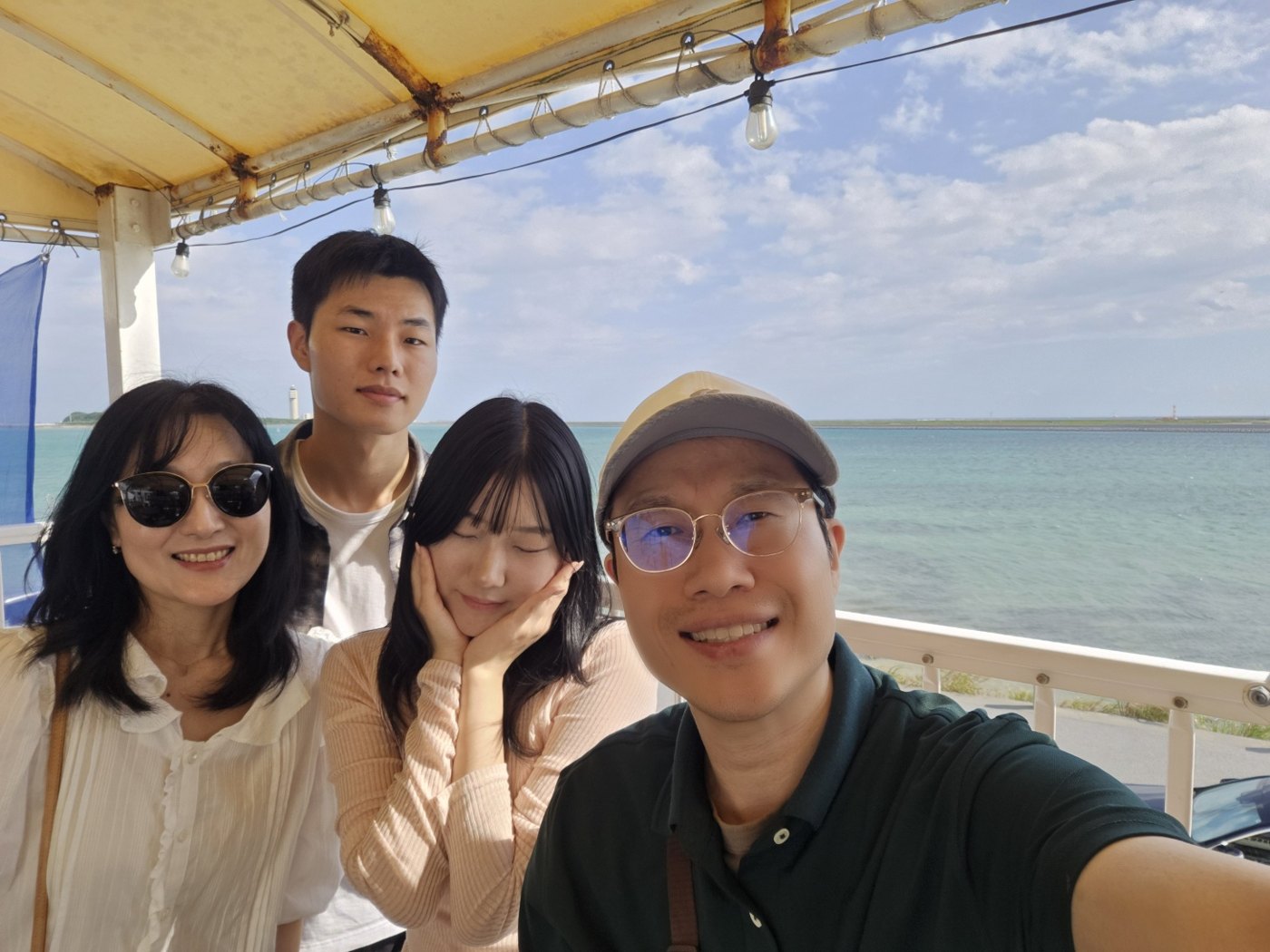 우미카지 테라스 바다 앞에서 찍은 가족 네 명 셀카
